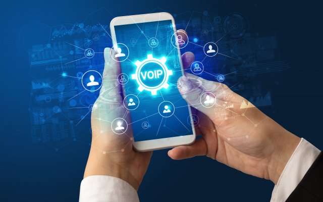 voip services best residential voip providers home voip 2020 man holding smartphone voip on display blue background